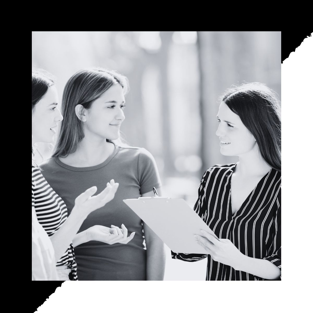 Black and white Image of a woman holding a clipboard, engaging three woman in a community survey to effectively get more responses to her community survey.