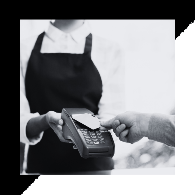 Black and white close up image of a man tapping his debit card on a POS machine to make a purchase from a store owner, depicting how customer retention increases repeat sales.